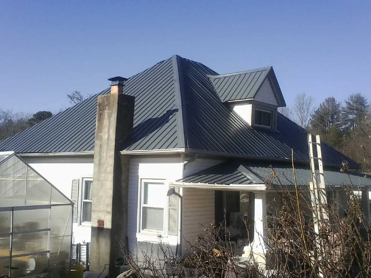 Dark blue standing seam metal roof on a white farmhouse with dormer — Slate & Tile Roof Repair by Roofing Brothers in Huntingdon