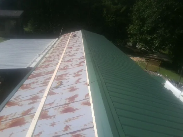 Old rusted panels beside newly installed green metal roofing — Wind Damage Roof Repair by Roofing Brothers in Huntingdon