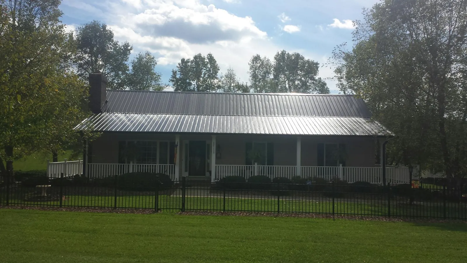 Gray metal roof on a brick ranch with a full width front porch — Gutter Guard Installation work by our crew in Huntingdon